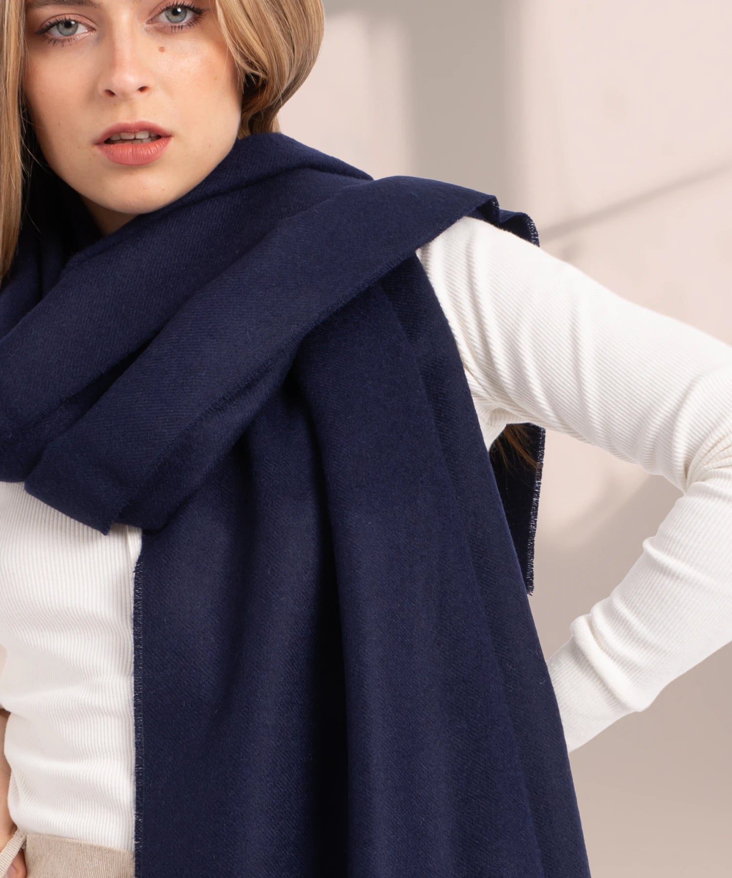 Woman wearing a navy blue scarf over a white shirt against a neutral background