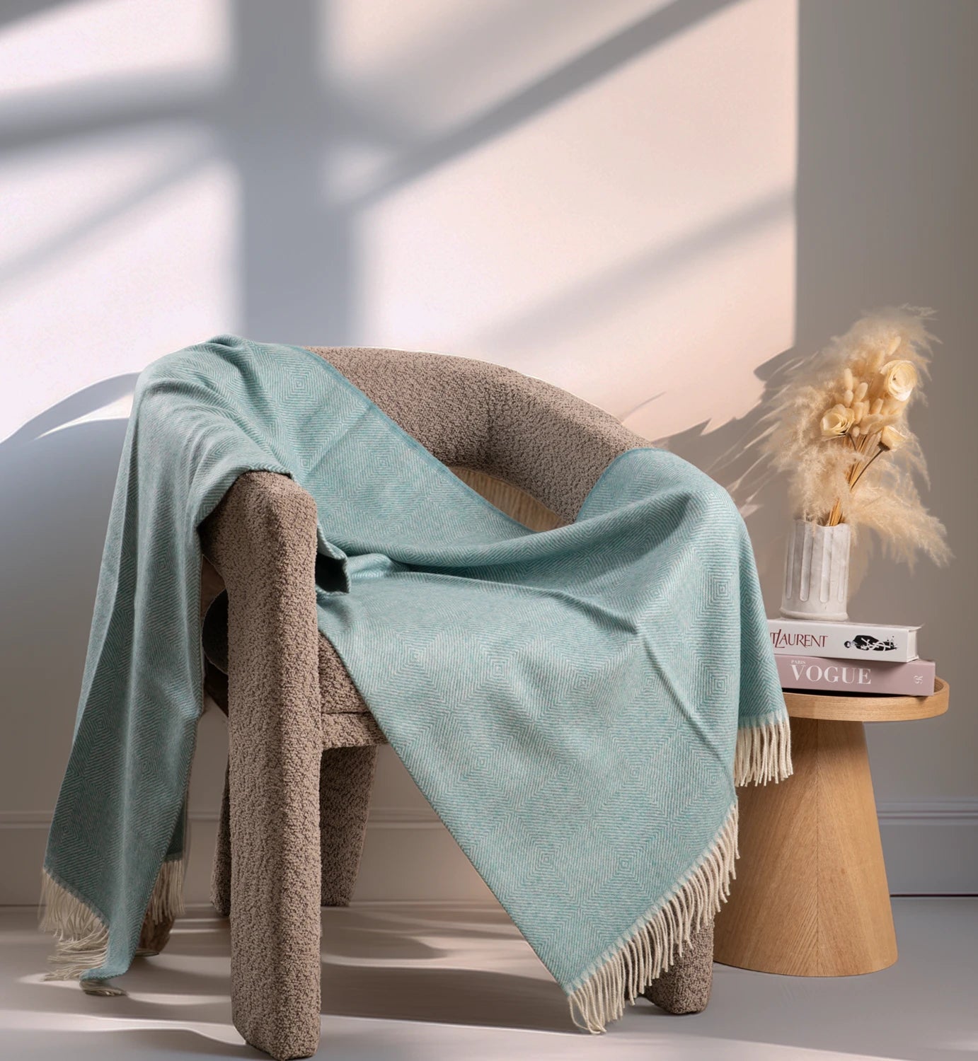Light blue blanket draped over a textured chair with a wooden side table and decorative items in the background.