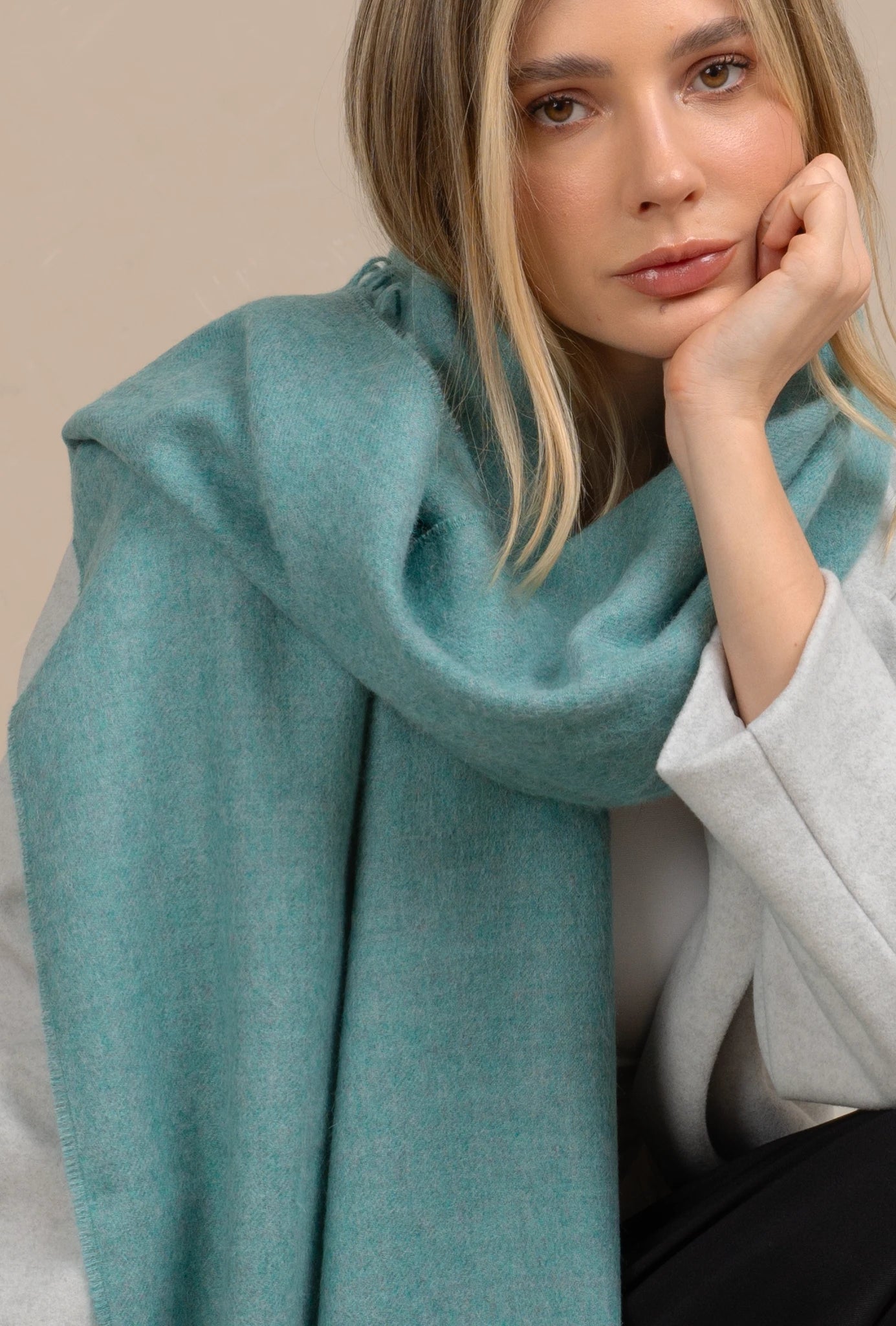 Woman wearing a teal scarf with a neutral background