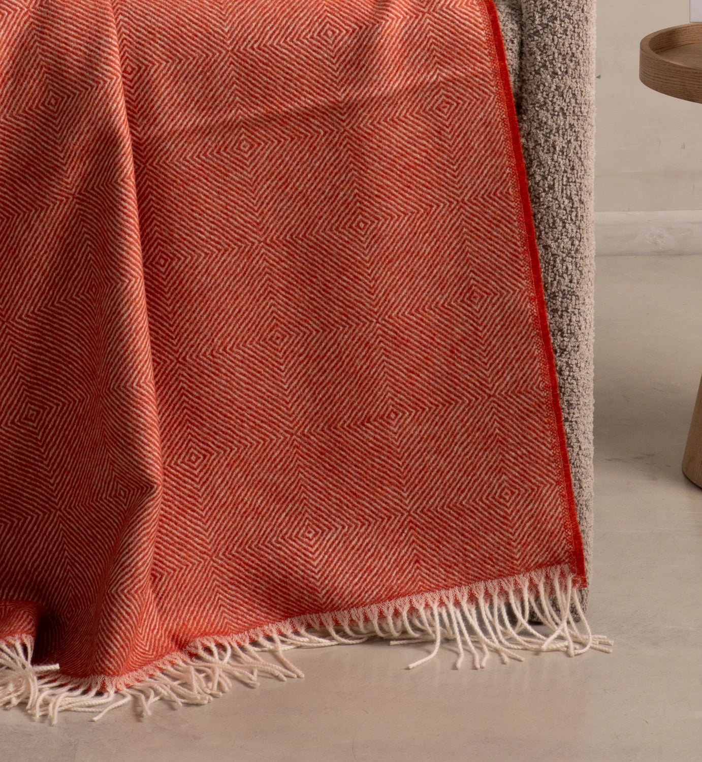 Red patterned throw blanket with white fringe on a neutral background