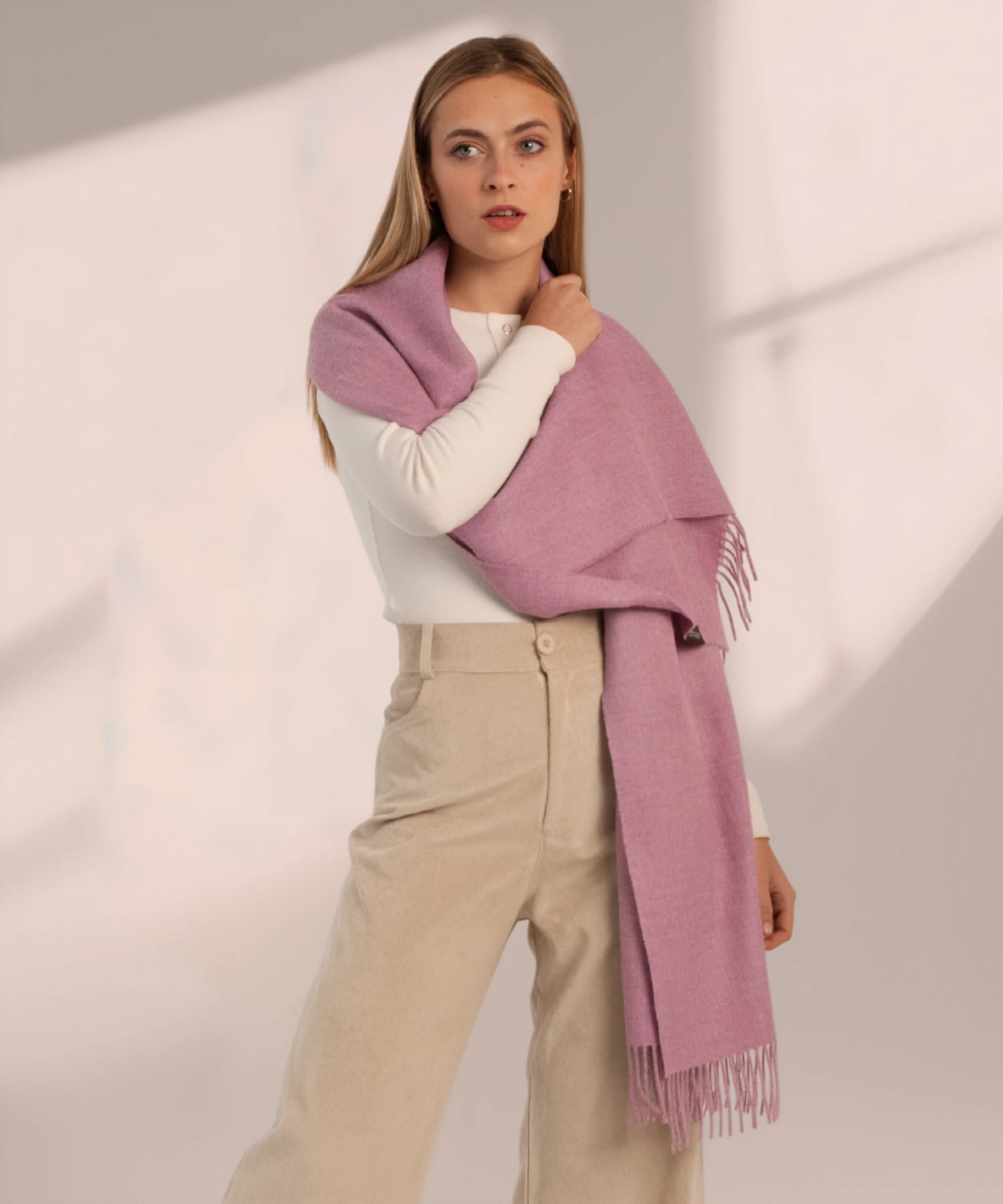 Woman wearing a pink scarf with a plain background