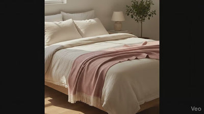 video de una habitacion color crema con una manta color rosa encima 