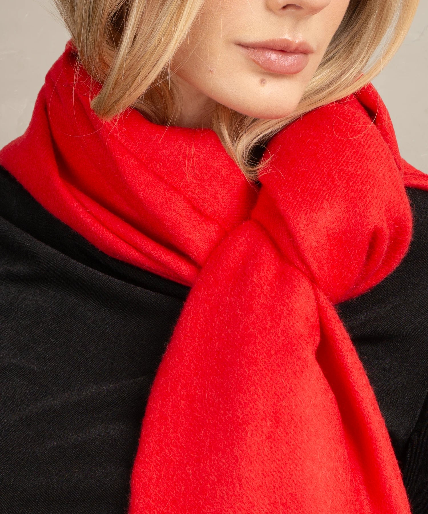 Close-up of a person wearing a bright red scarf with a neutral background