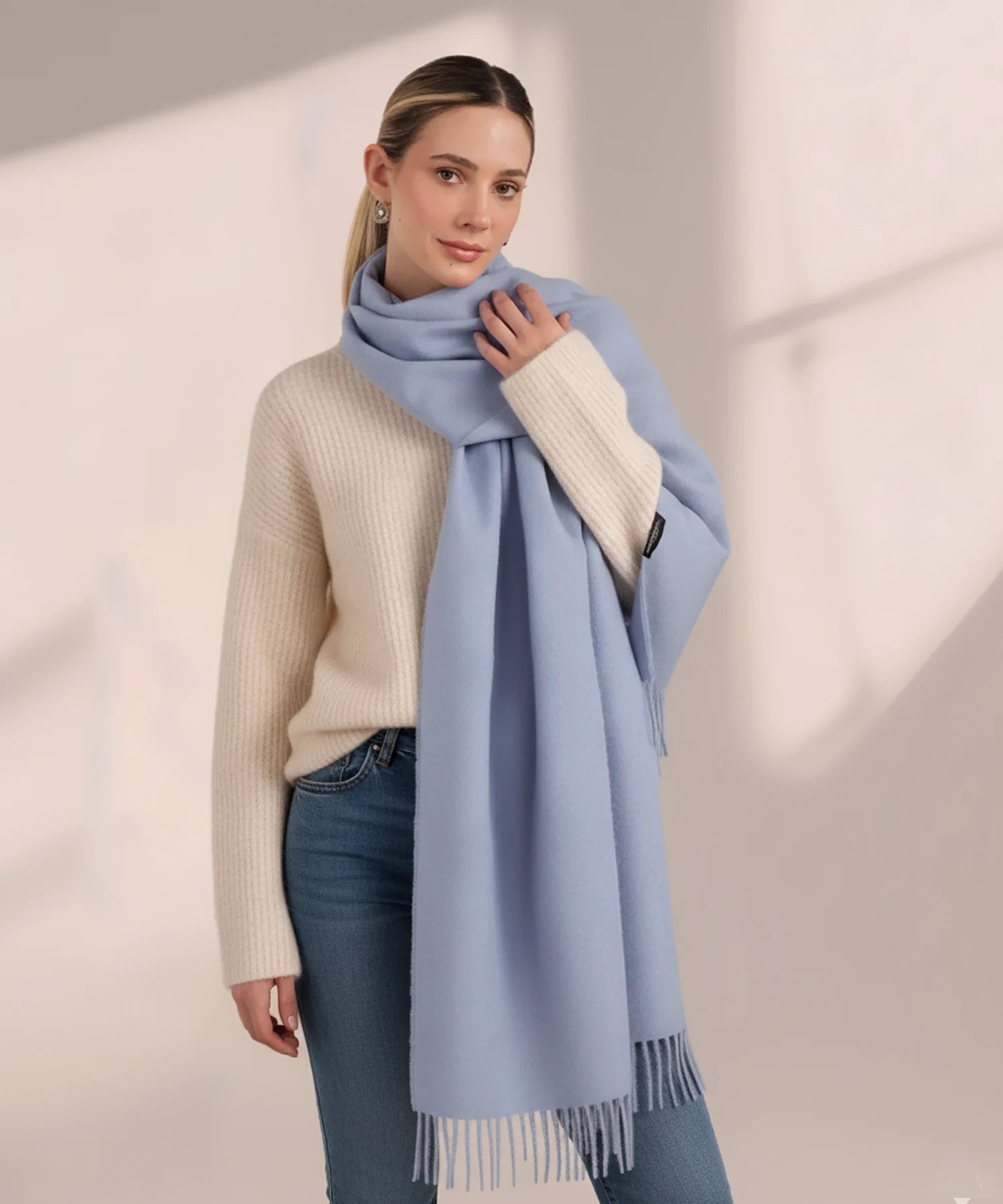 Woman wearing a light blue scarf on a plain background