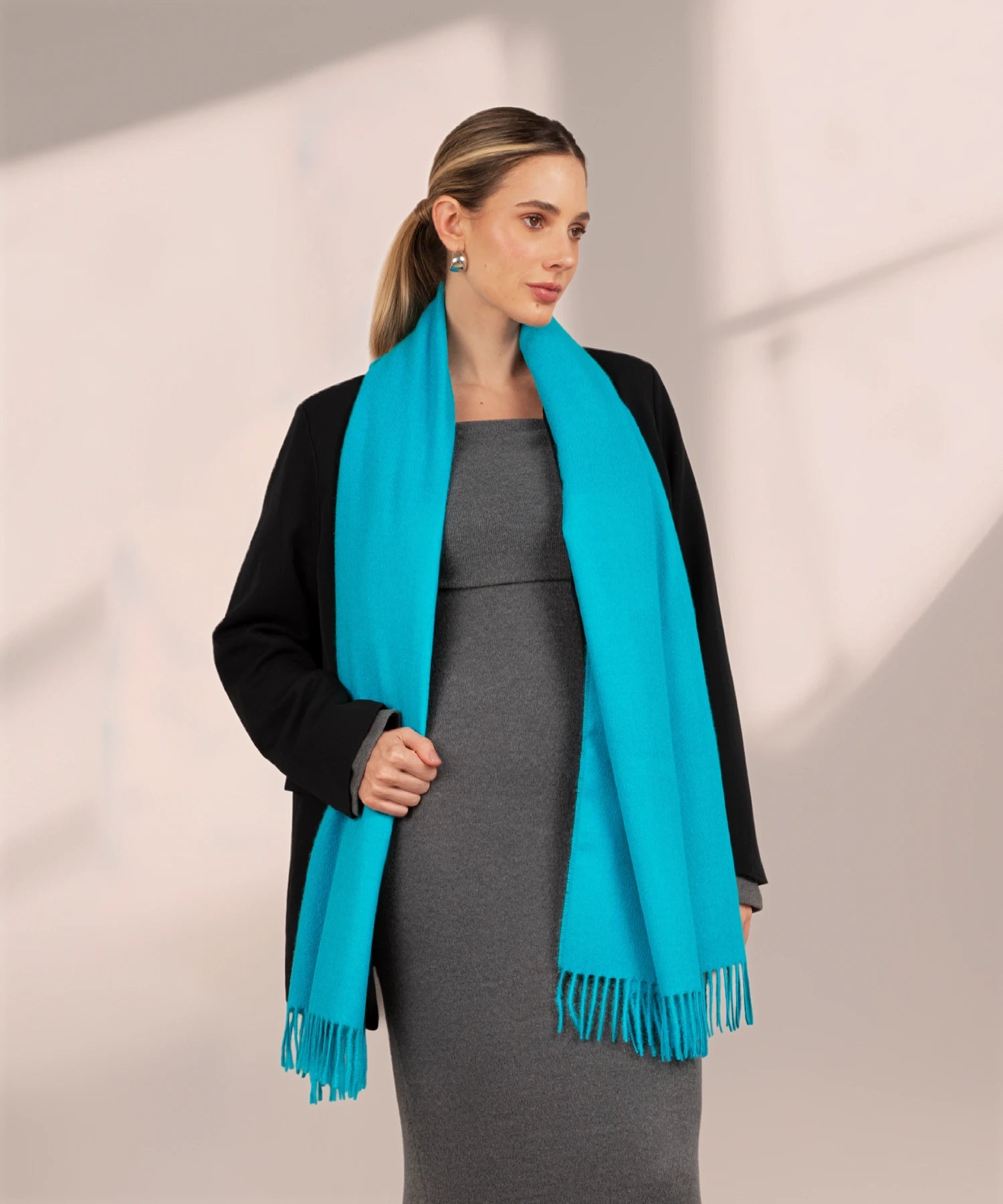 Woman wearing a turquoise scarf with a plain background